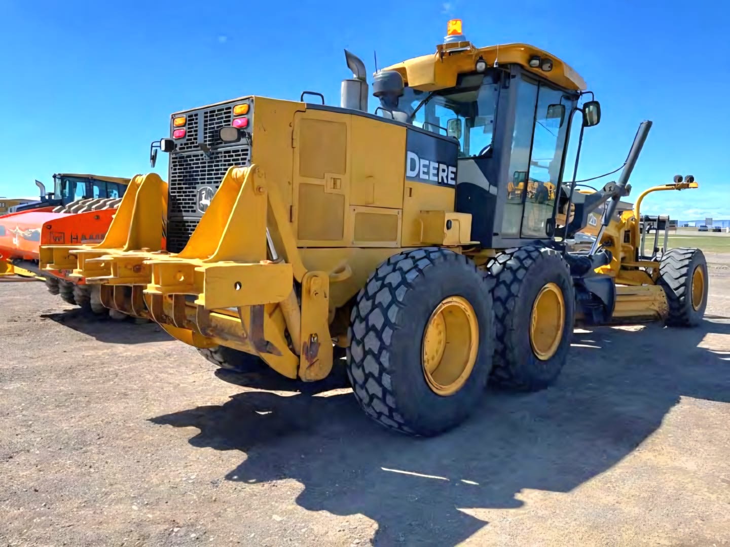 Motoconformadora John Deere 772D, vista trasera junto a otro equipo